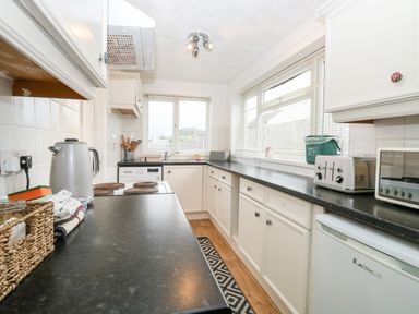 A kitchen with white cabinets black countertops and various appliances at Phloxhaven in Reedham