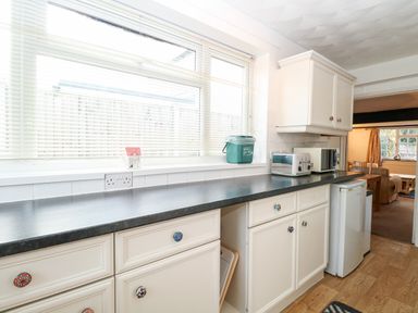 A kitchen countertop with a toaster microwave and small fridge and cabinets at Phloxhaven in Reedham