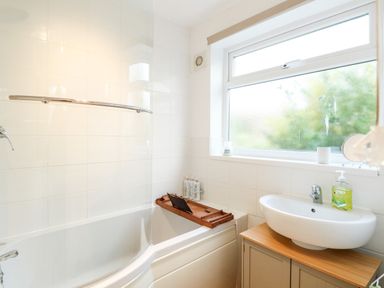 A bathroom with a bathtub and a sink under a window at Phloxhaven in Reedham