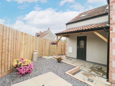 A small backyard with tiled floor gravel flower pots and wooden fence at Bramley Cottage in Henley near Langport