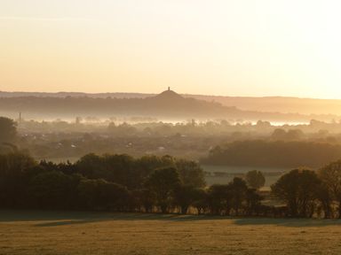 A landscape view of a town with trees and a hill with a monument at Bramley Cottage in Henley near Langport