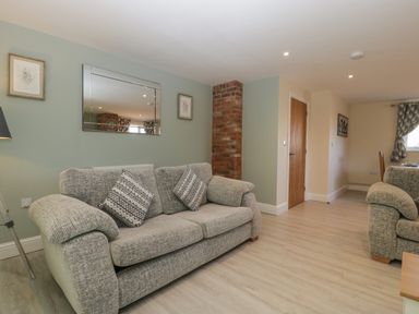 A living room with two sofas a mirror and a brick column at Bramley Cottage Henley near Langport
