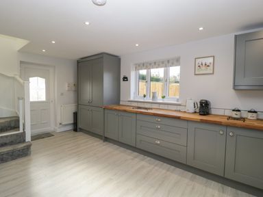 A kitchen with grey cabinets wooden countertop and appliances near a window at Bramley Cottage Henley near Langport