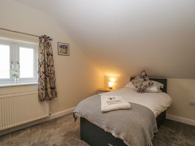 A bedroom with a double bed bedside table with lamp a window with curtain and a framed picture at Bramley Cottage in Henley near Langport