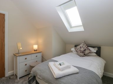 A bedroom with a bed a chest of drawers a small stool and a skylight window at Bramley Cottage Henley near Langport