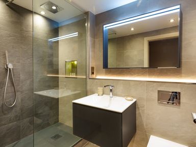 A bathroom with a walk-in shower a wall-mounted sink and a lighted mirror at Carus House at Carus Green Golf Club in Kendal