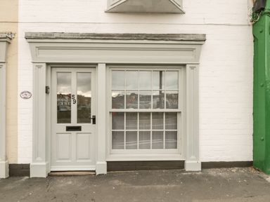 A white front door with number 59 and a window next to it on a white brick building at Swallows Nest in Whitby