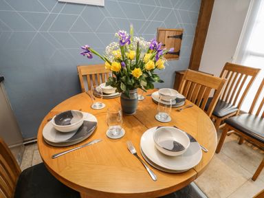 A dining table set with plates bowls glasses cutlery and a flower vase with yellow and purple flowers at Swallows Nest Whitby