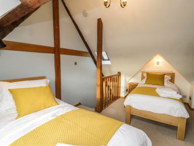 A bedroom with two single beds with yellow bedding and exposed wooden beams at Swallows Nest in Whitby