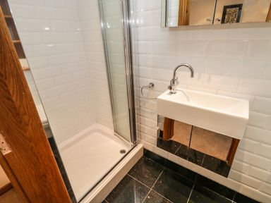 A bathroom with a corner shower and a wall-mounted sink at Swallows Nest in Whitby