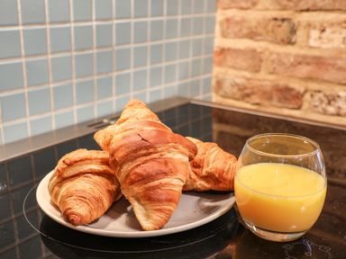 Three croissants on a plate next to a glass of orange juice on a kitchen countertop at Swallows Nest in Whitby