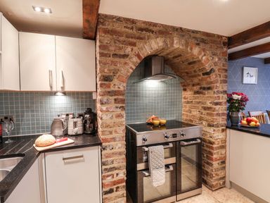 A kitchen with a stove in a brick arch and countertop appliances at Swallows Nest in Whitby