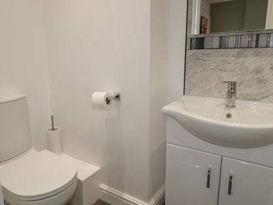 A bathroom with a toilet and a sink with cabinet at 23 Carmen Sylva Road in Llandudno