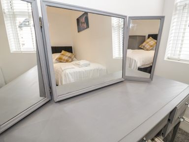 A bedroom reflected in a three-panel mirror on a grey dressing table at 23 Carmen Sylva Road in Llandudno