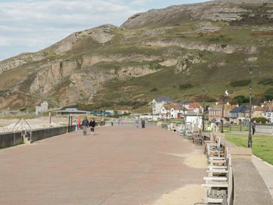 A coastal promenade with benches and street lamps near houses and hills at 23 Carmen Sylva Road in Llandudno