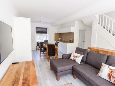A living room with a gray sofa and wooden table next to a dining area with wooden table and chairs at 8 Waterhead Terrace Ambleside