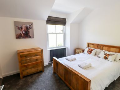 A bedroom with a wooden bed and dresser and animal pillows on the bed at 8 Waterhead Terrace in Ambleside