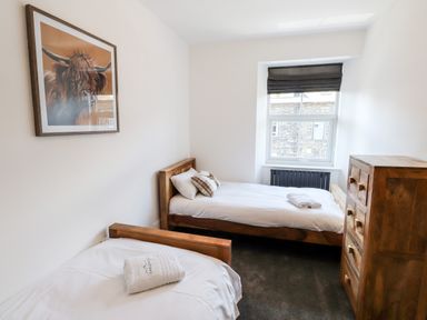 A bedroom with two single beds a chest of drawers and a window at 8 Waterhead Terrace in Ambleside