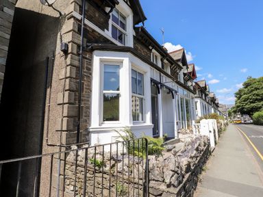 A row of terraced houses with stone walls along a sidewalk at 8 Waterhead Terrace in Ambleside