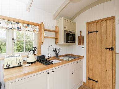 A kitchen countertop with a toaster kettle sink and stove next to a wooden door at Waylands in Uffington