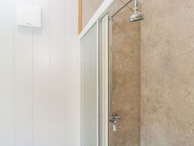 A shower area with a chrome showerhead and beige tiled walls at Waylands in Uffington
