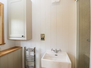 A bathroom sink with a chrome faucet a metal towel rack a wall cabinet and a glass shower enclosure at Waylands in Uffington