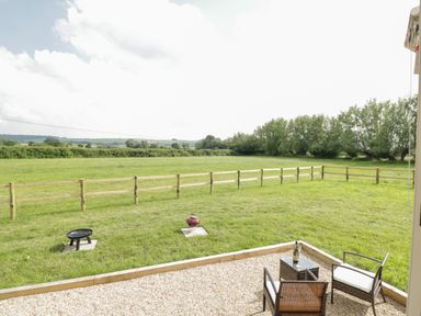 A garden with a small fenced area two fire pits and a seating area with two chairs and a table at Waylands in Uffington