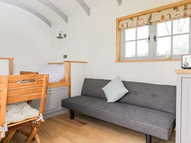 A room with a gray sofa and a wooden chair next to a built-in bed under a window at Ridgeway in Uffington