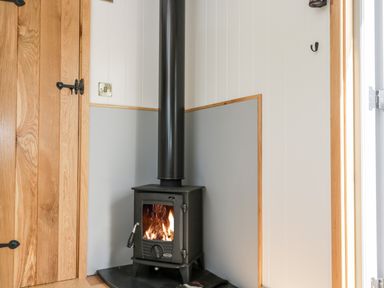 A corner of a room with a black wood-burning stove next to a wooden door at Ridgeway in Uffington