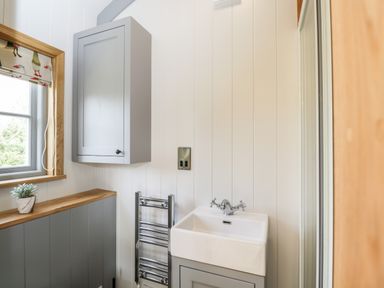 A bathroom with a sink cabinet a wall cabinet a window with a patterned blind and a towel radiator at Ridgeway in Uffington