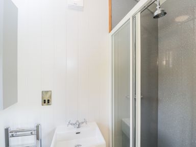 A bathroom with a white sink and chrome faucet next to a shower with glass sliding doors at Ridgeway in Uffington