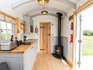 A kitchen area with wooden countertops a toaster a kettle a stove and a wood burning stove at Ridgeway in Uffington
