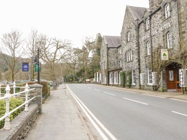 A street view with stone buildings including Royal Oak Hotel and sidewalk with trees in a village