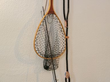 A fishing net and rod hanging on a textured wall at Dolwen in Penmachno