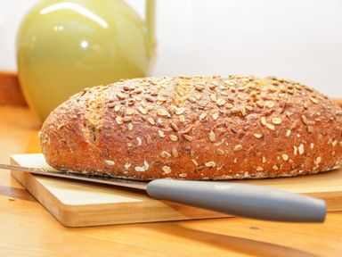 A loaf of seed bread on a cutting board with a knife and a teapot in the background at Dolwen in Penmachno