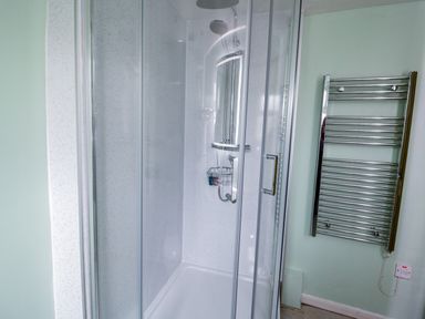 A shower enclosure with glass doors and a chrome heated towel rail in a bathroom at Dolwen in Penmachno