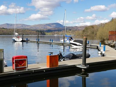A marina with boats docked on the water and hills in the background at Grizedale Lodge Langdale 18 White Cross Bay near Windermere