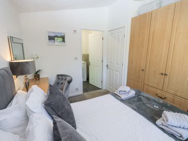 A bedroom with a bed pillows towels a lamp chair wardrobe and an open door showing a bathroom at Grizedale Lodge Langdale 18 White Cross Bay near Windermere