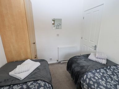 A bedroom with two single beds a wooden wardrobe a radiator and a door at Grizedale Lodge Langdale 18 White Cross Bay near Windermere