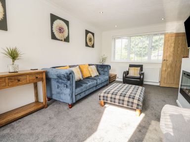 A living room with a blue sofa and plaid ottoman at 26 Hycemoor Way Bootle Near Millom