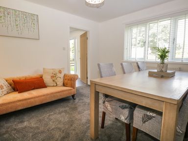 A dining room with table and chairs near a window and a sofa with cushions at 26 Hycemoor Way Bootle Near Millom