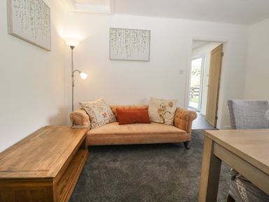 A living room with a sofa and pillows a wooden table and a floor lamp at 26 Hycemoor Way Bootle Near Millom