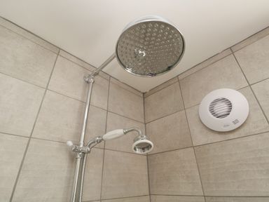 A tiled shower corner with two showerheads and a ventilation fan at 26 Hycemoor Way Bootle Near Millom