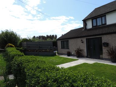 A front yard with green lawn bushes walkway and a two story house at 26 Hycemoor Way Bootle Near Millom