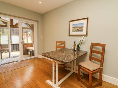 A dining area with a granite table and two wooden chairs next to glass doors at Nattaden @ Fourwinds Meldon near Okehampton