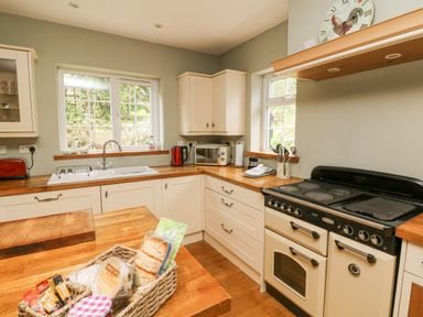 A kitchen with wooden countertops and cream cabinets at Nattaden @ Fourwinds Meldon near Okehampton