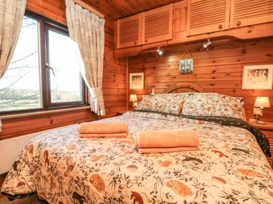 A bedroom with a bed covered in animal patterned bedding and two folded towels by a window at Holly Lodge in Liverton