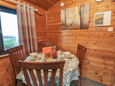 A dining area with a round table set for breakfast in a wooden room at Holly Lodge in Liverton