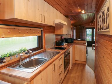 A kitchen with a sink stove microwave and cabinets at Holly Lodge in Liverton