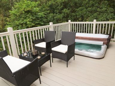 An outdoor deck with black wicker chairs a glass table and a hot tub at Number 43 Burnside Lodge in Felton